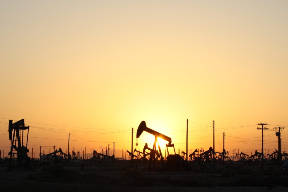 Bombas de extração de petróleo em campo petrolífero ao pôr do sol