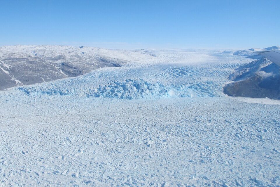 Aerial view of a glacier in southwest Greenland, with fractured ice between mountains, in April 2014